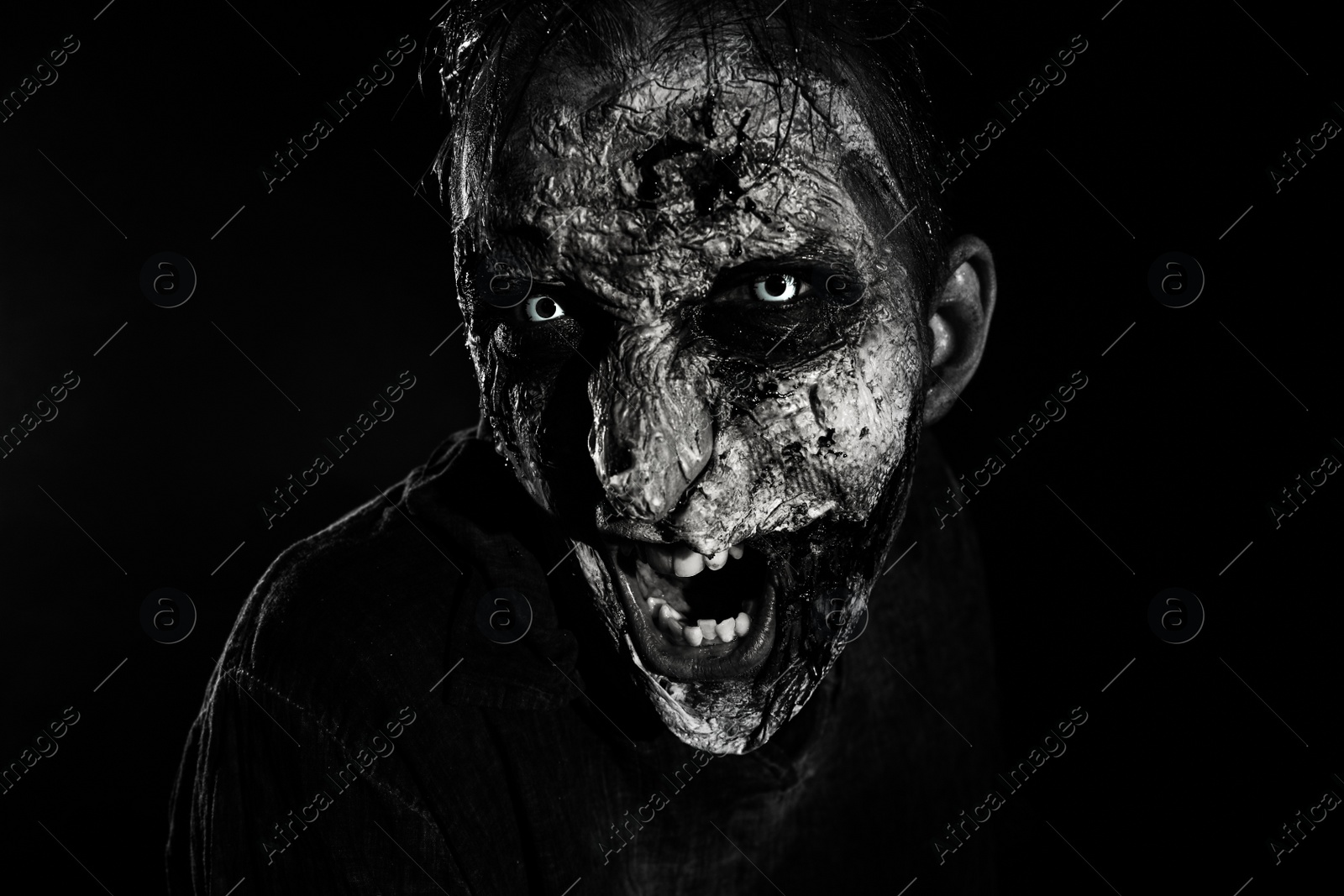 Photo of Scary zombie on dark background, black and white effect. Halloween monster