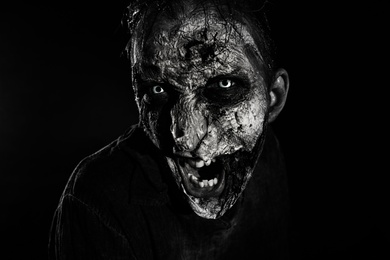 Photo of Scary zombie on dark background, black and white effect. Halloween monster