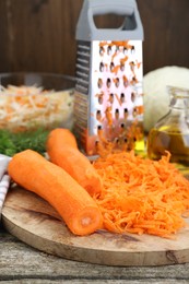 Photo of Cooking delicious sauerkraut soup. Fresh chopped carrot on wooden table, closeup