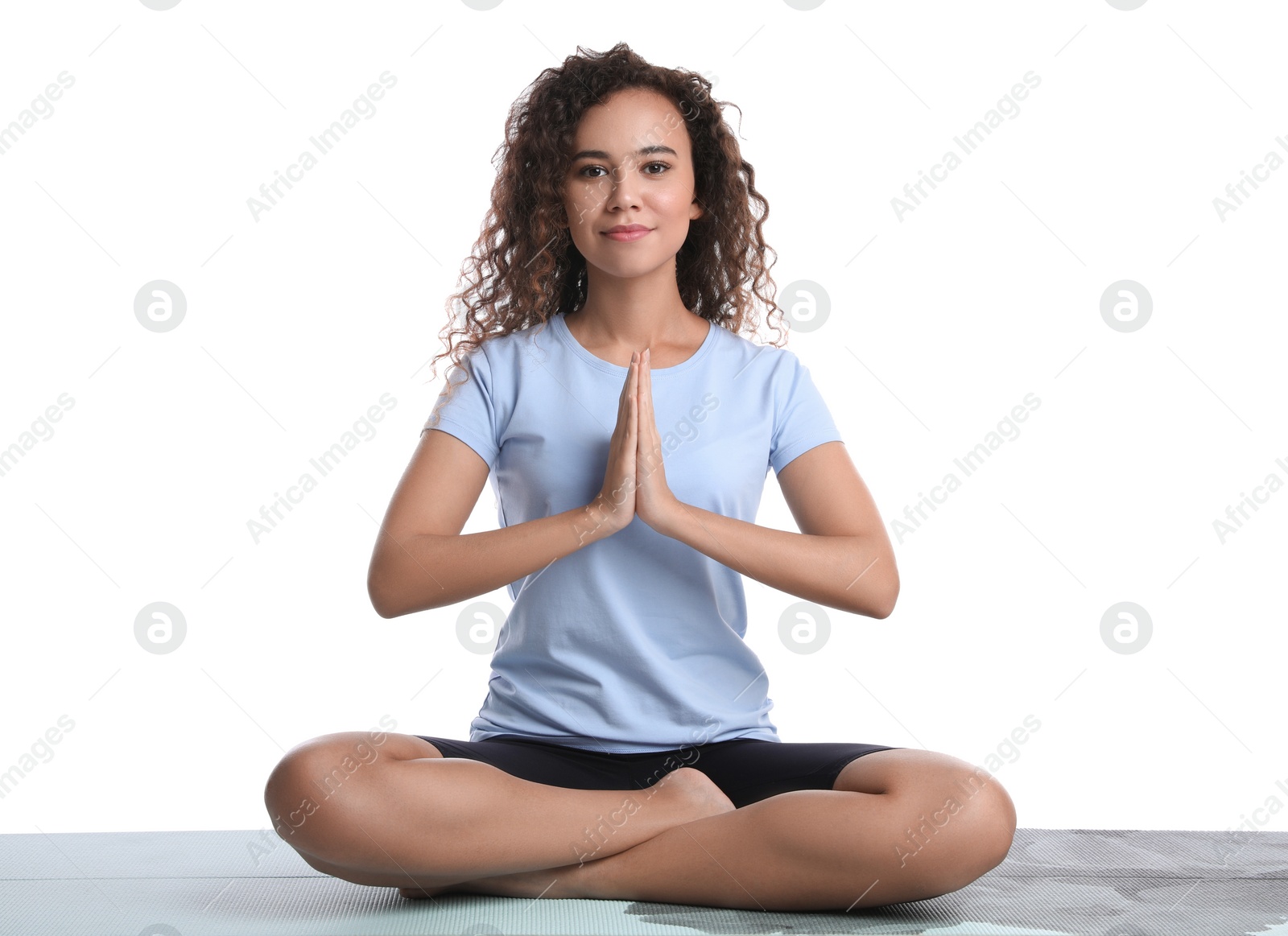 Photo of Beautiful African-American woman meditating on yoga mat against white background