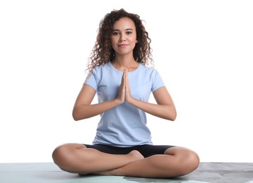 Photo of Beautiful African-American woman meditating on yoga mat against white background