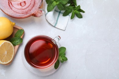 Photo of Cup of hot aromatic tea with mint and lemon on light grey table, flat lay. Space for text