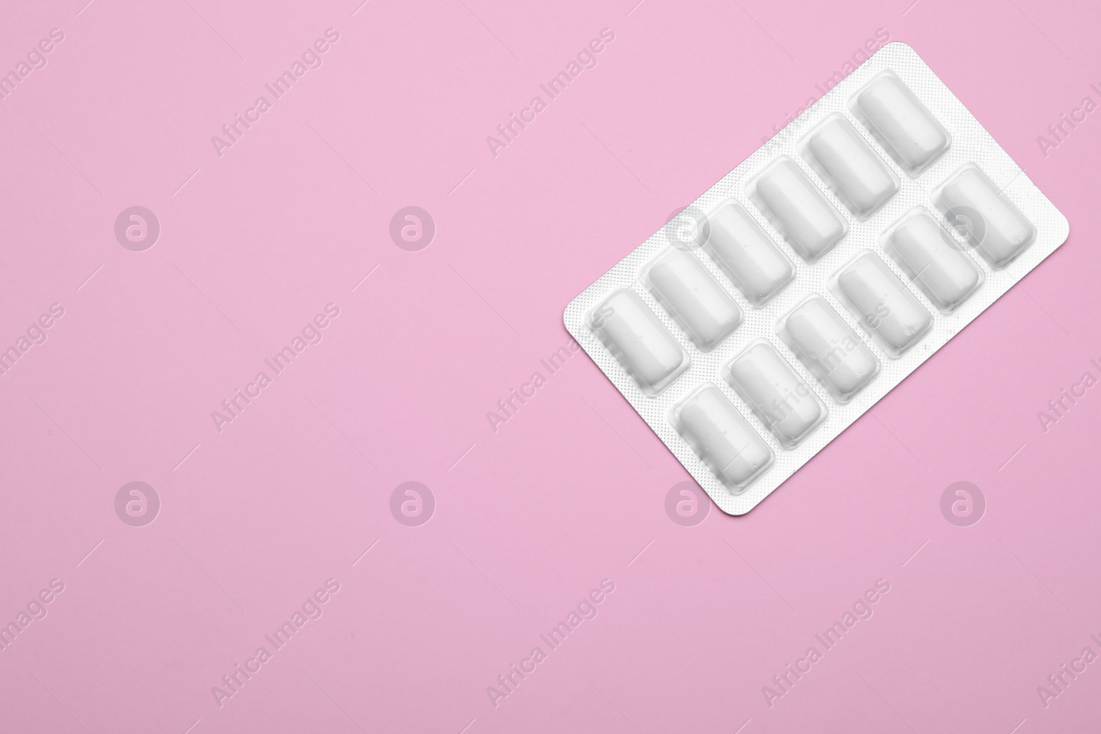 Photo of Blister with chewing gums on pink background, top view. Space for text