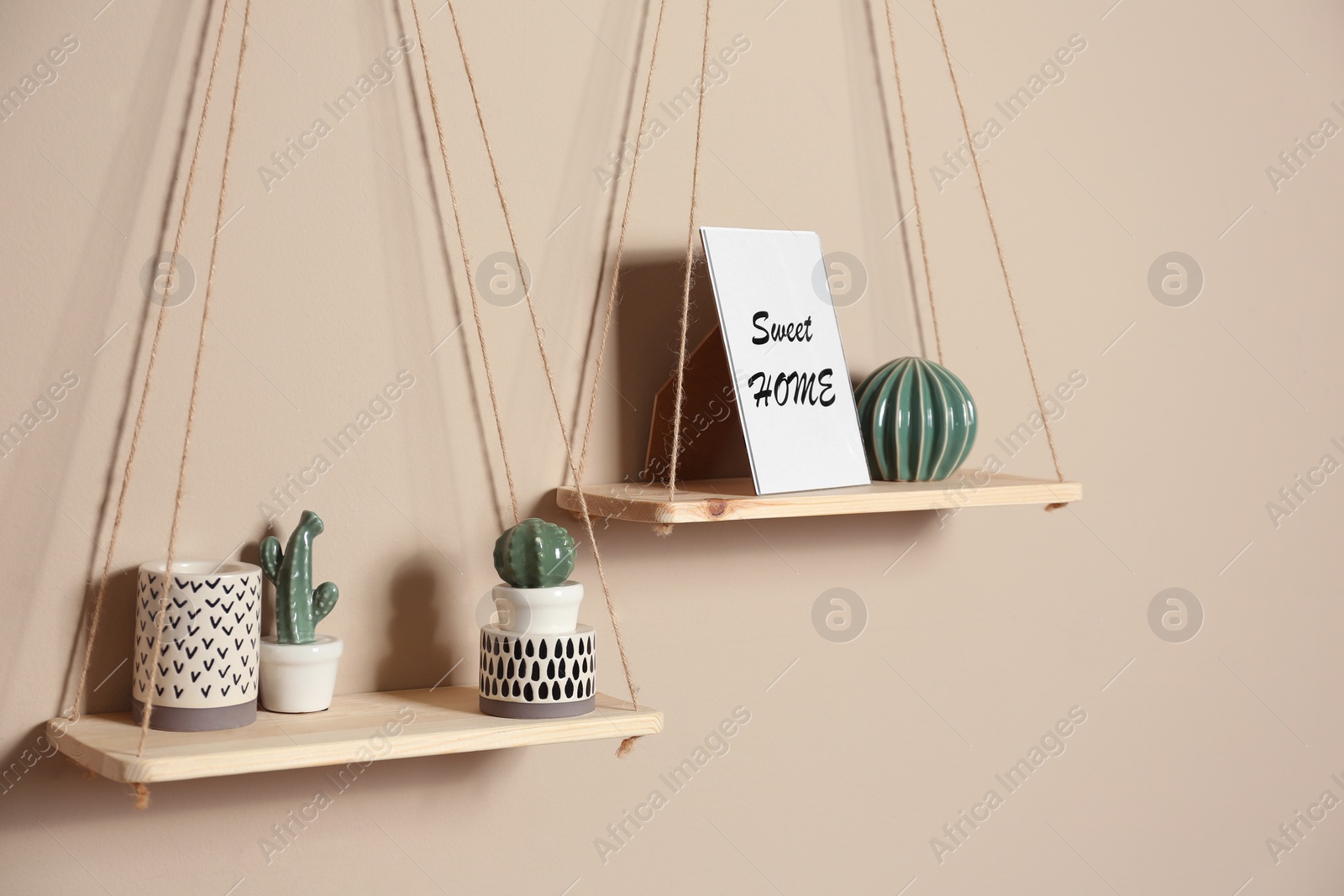 Photo of Wooden shelves with different decorative elements on beige wall