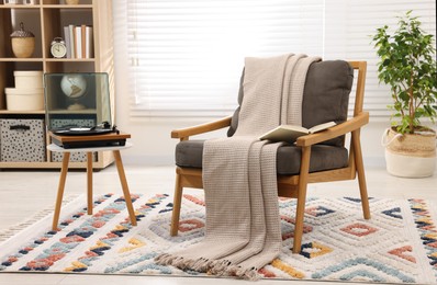 Stylish living room interior with comfortable armchair and blanket