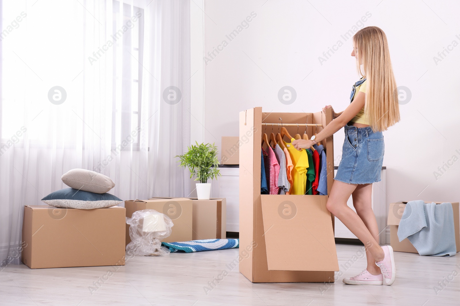 Photo of Young woman near wardrobe box at home