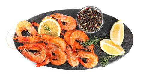 Delicious cooked shrimps served with lemon, pepper and rosemary on white background, top view