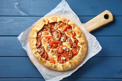 Tasty galette with tomato and cheese (Caprese galette) on blue wooden table, top view