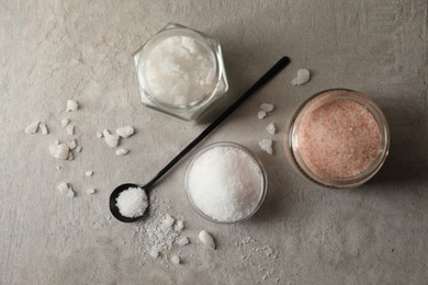 Photo of Different natural salt on grey textured table, flat lay