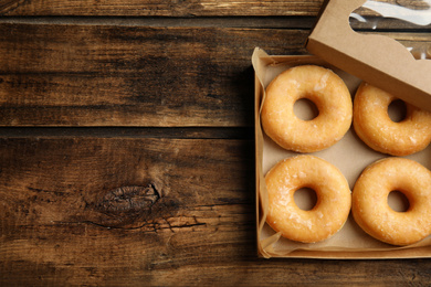 Delicious donuts on wooden table, top view. Space for text