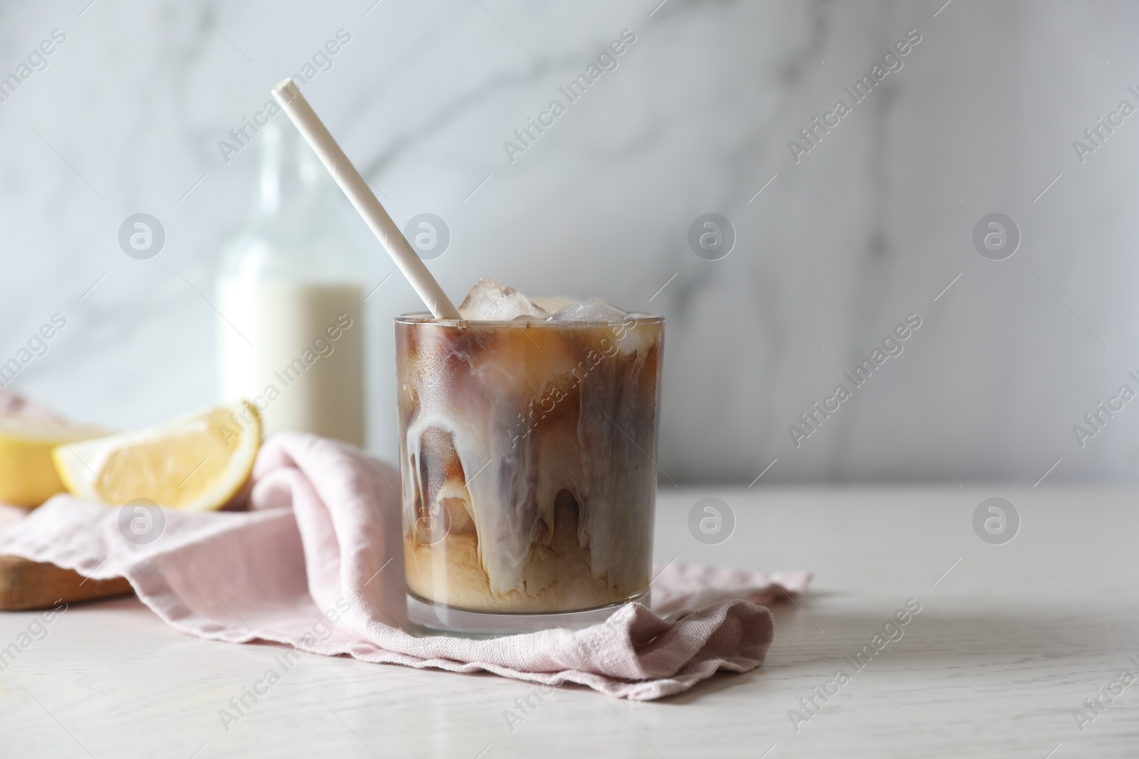 Photo of Refreshing iced coffee with milk in glass on white wooden table