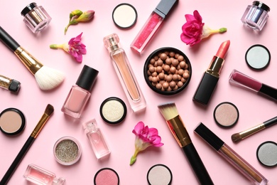 Different makeup products with flowers on color background