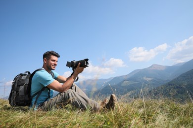 Photo of Professional photographer taking picture with modern camera in mountains. Space for text