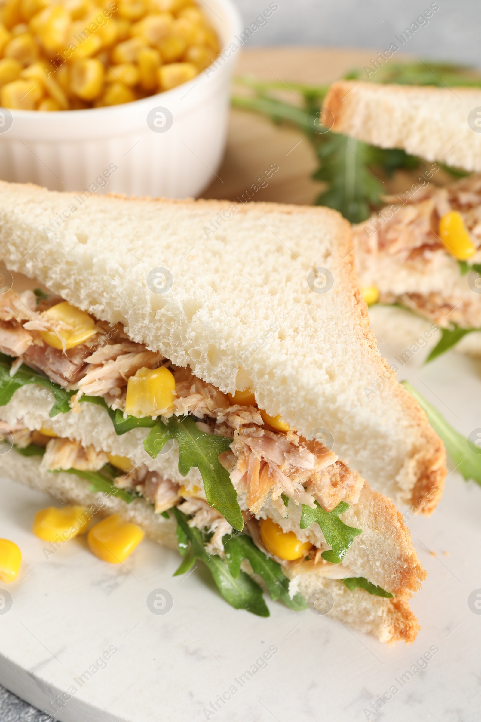 Photo of Delicious sandwiches with tuna, corn and greens on serving board, closeup