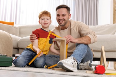 Photo of Father and son measuring shelf together at home. Repair work