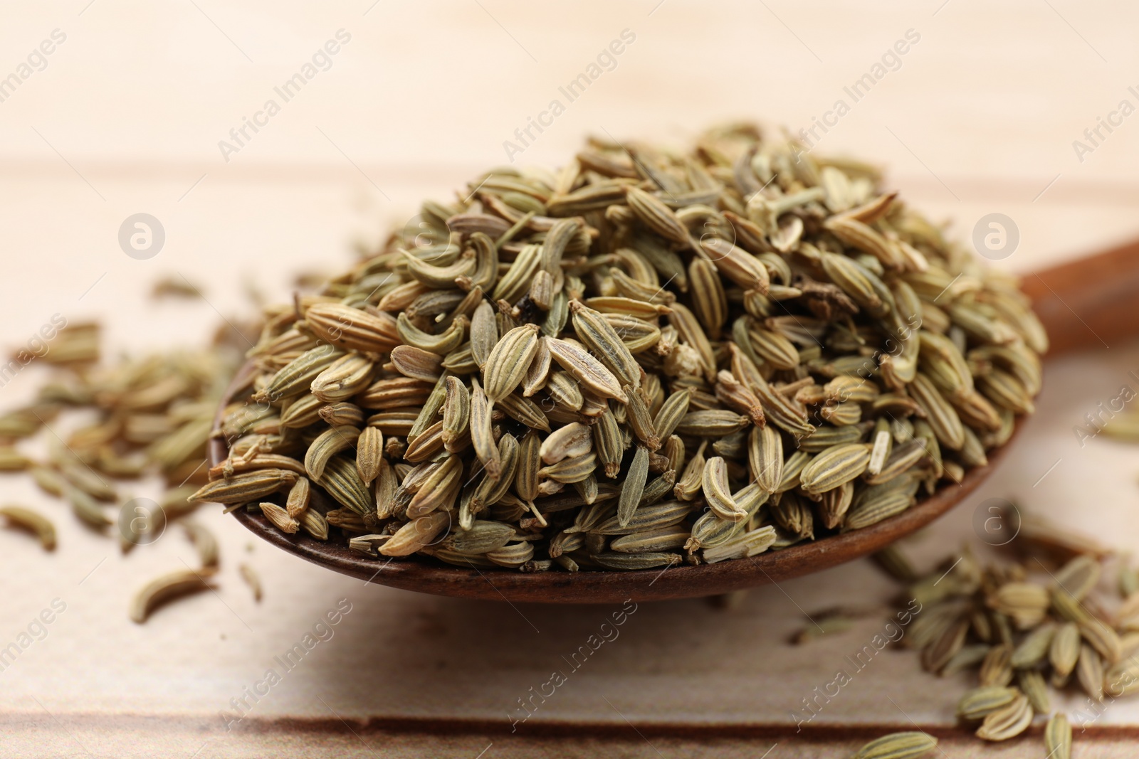 Photo of Spoon of fennel seeds on table, closeup