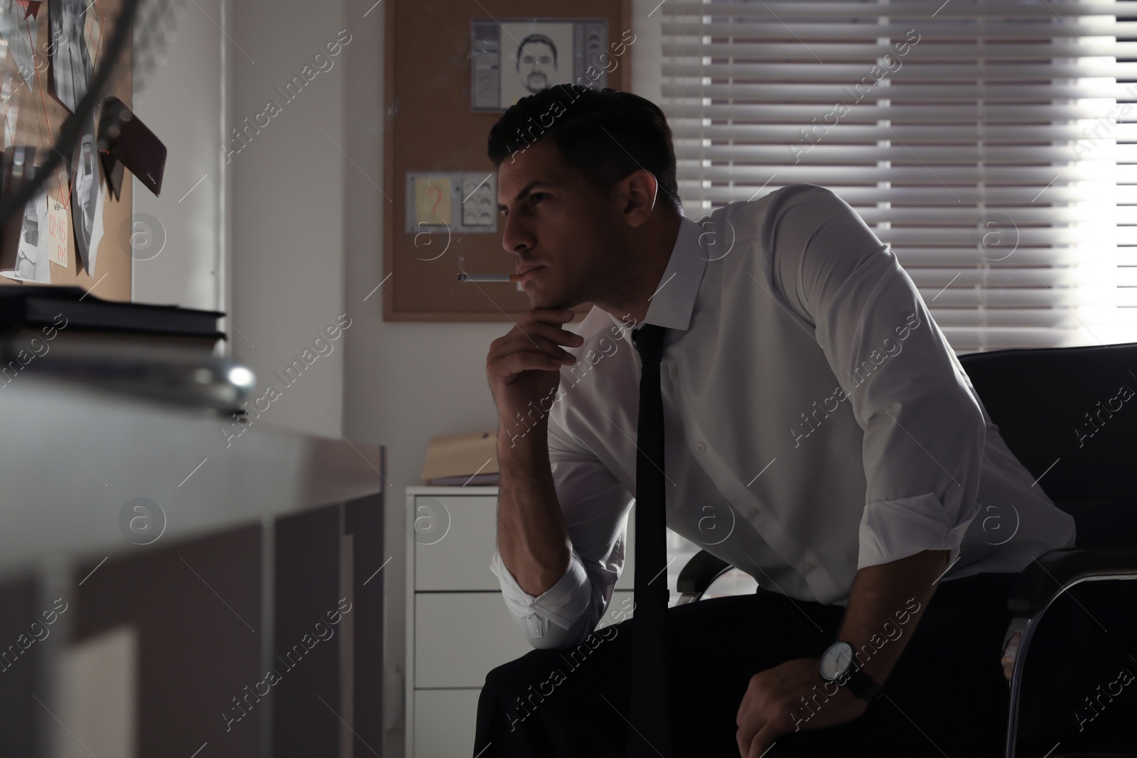 Photo of Professional detective smoking cigarette in his office