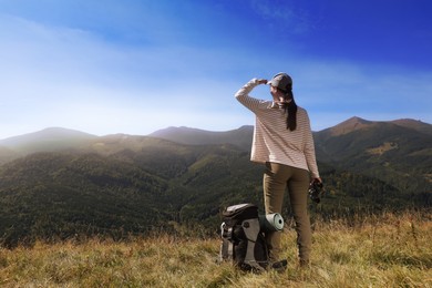 Photo of Tourist with hiking equipment and binoculars in mountains, back view