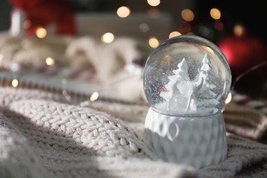 Christmas snow globe with knitting clothes on blurred background. Space for text