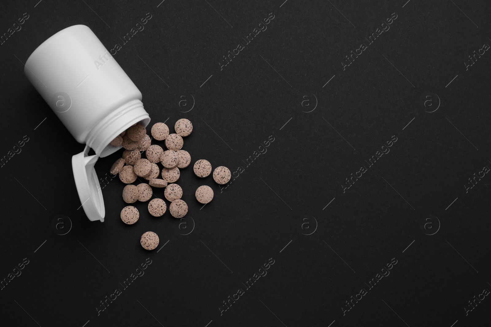 Photo of Jar with brewer`s yeast tablets on black background, flat lay. Space for text