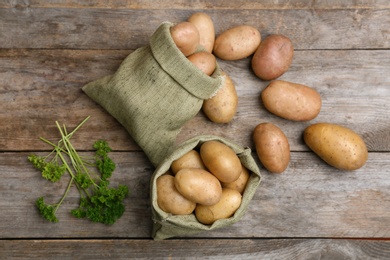 Photo of Flat lay composition with fresh ripe organic potatoes on wooden background