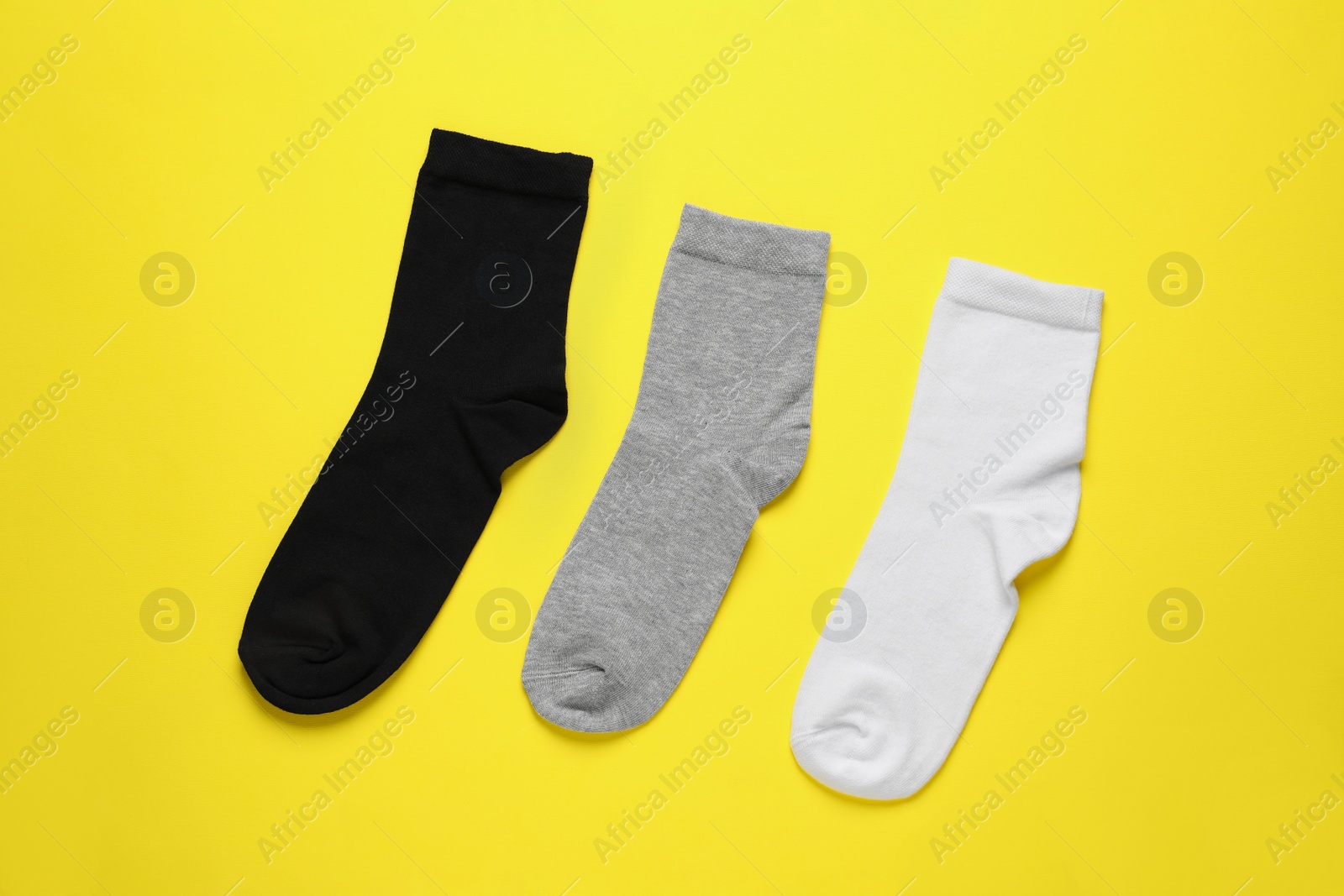 Photo of Different socks on yellow background, flat lay