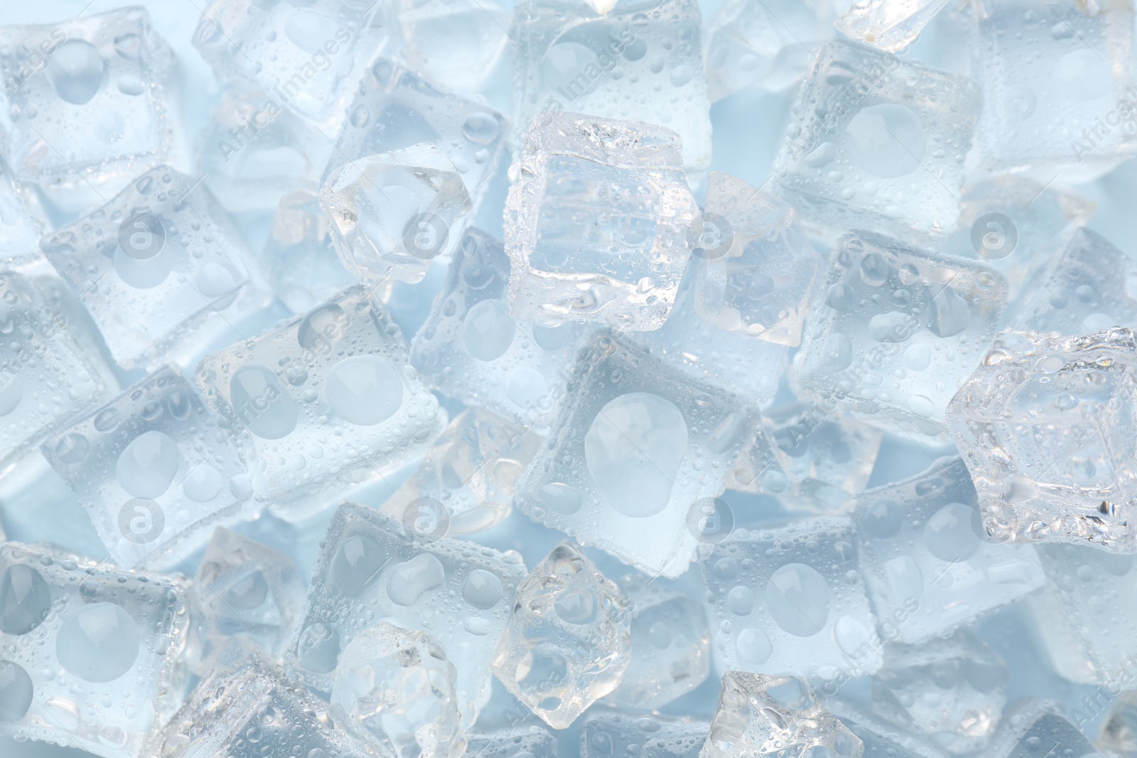 Photo of Crystal clear ice cubes on light blue background, flat lay