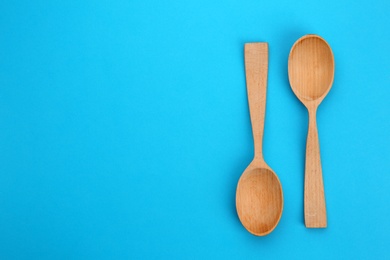 Clean empty wooden spoons on blue background, flat lay. Space for text