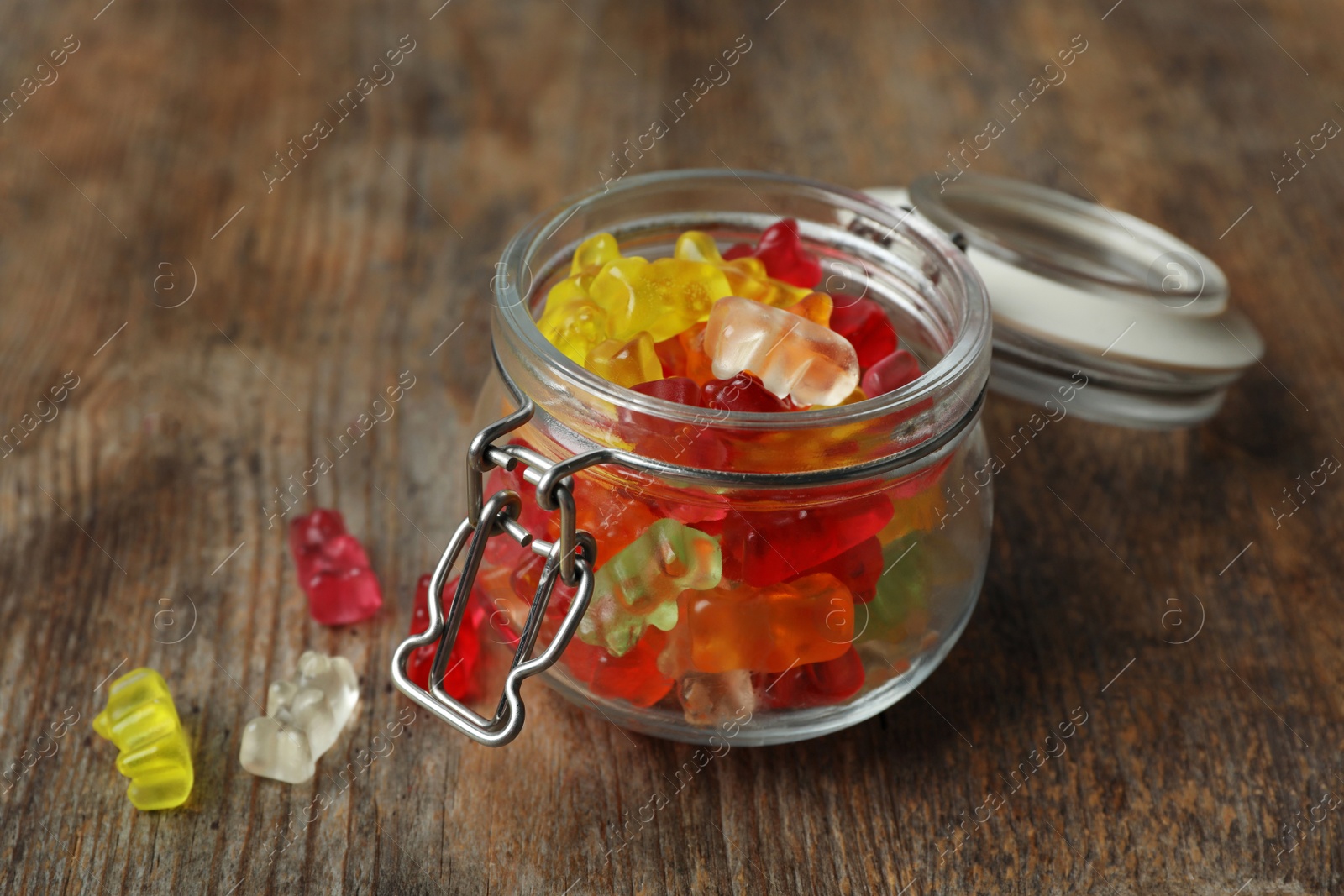 Photo of Open glass jar with delicious jelly bears on wooden table