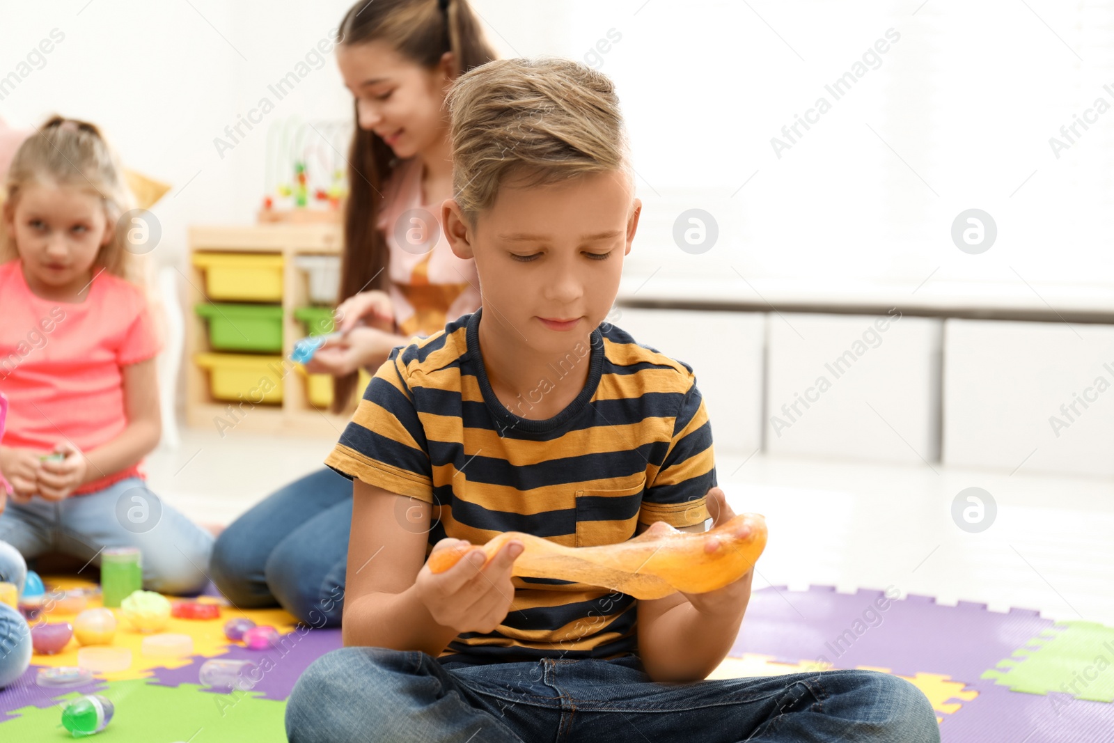 Photo of Preteen boy playing with slime in room