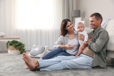 Photo of Happy family with their cute baby on floor in living room