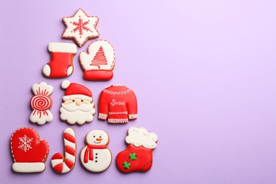 Photo of Christmas tree shape made of delicious gingerbread cookies on lilac background, flat lay. Space for text