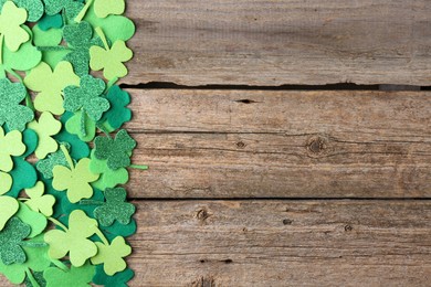 Photo of St. Patrick's day. Decorative clover leaves on wooden background, top view. Space for text