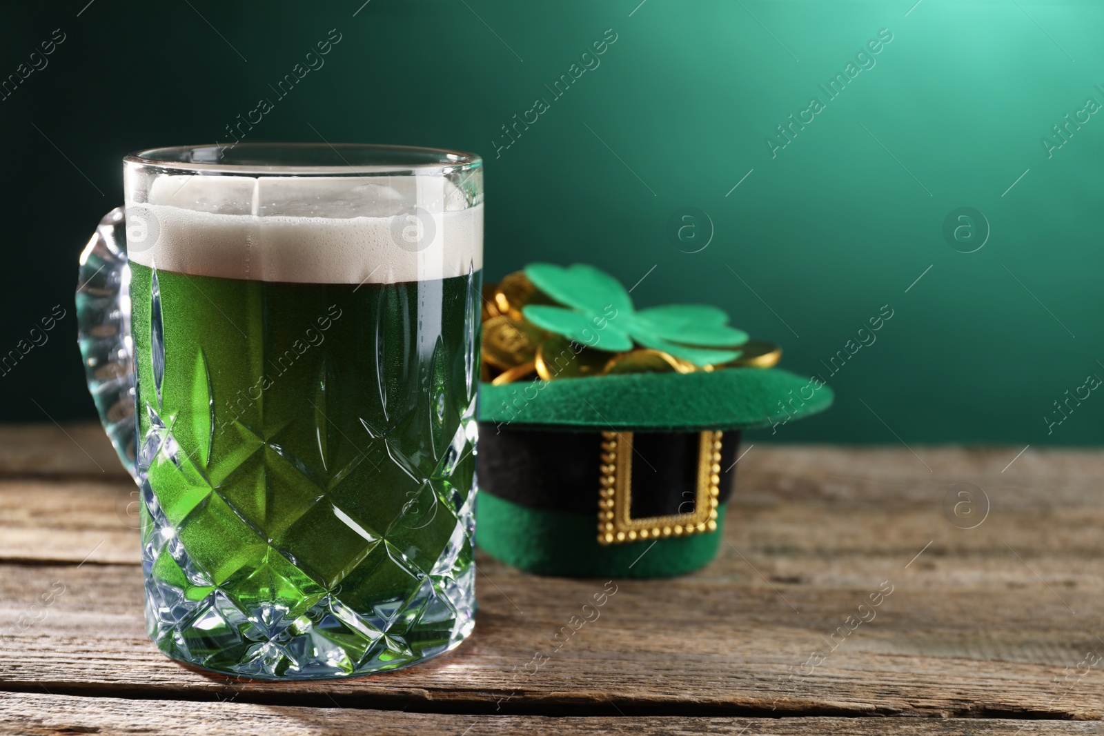 Photo of St. Patrick's day celebration. Green beer, leprechaun hat with gold and decorative clover leaf on wooden table. Space for text