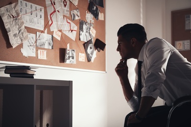 Photo of Detective looking at evidence board in office