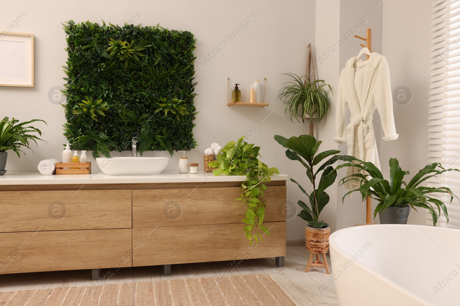 Photo of Green artificial plants, vanity and different personal care products in bathroom