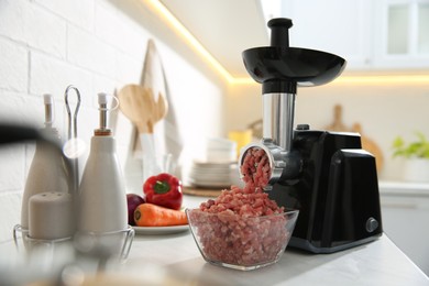 Photo of Modern meat grinder and products on white table in kitchen