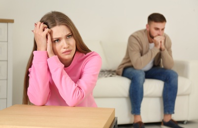 Photo of Young couple ignoring each other after argument in living room. Relationship problems