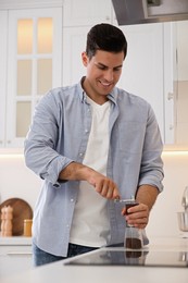 Photo of Man using manual coffee grinder in kitchen
