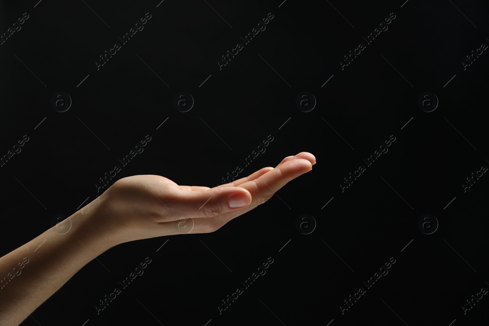 Photo of Woman holding something in hand on black background, closeup. Space for text