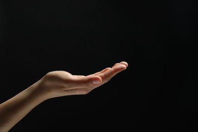 Woman holding something in hand on black background, closeup. Space for text