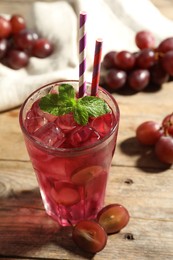 Photo of Delicious grape soda water with mint and berries on wooden table. Refreshing drink