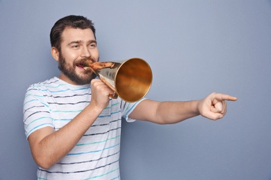 Photo of Young man shouting into megaphone on grey background
