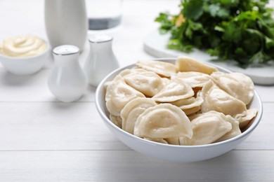 Delicious dumplings in bowl on white wooden table. Space for text