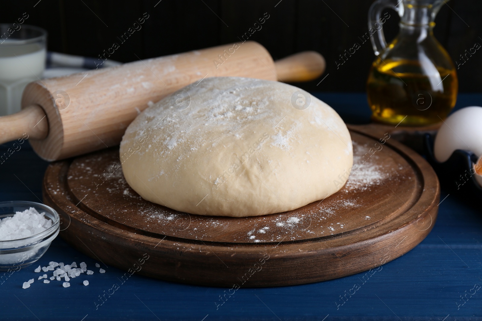 Photo of Fresh yeast dough and ingredients on blue wooden table