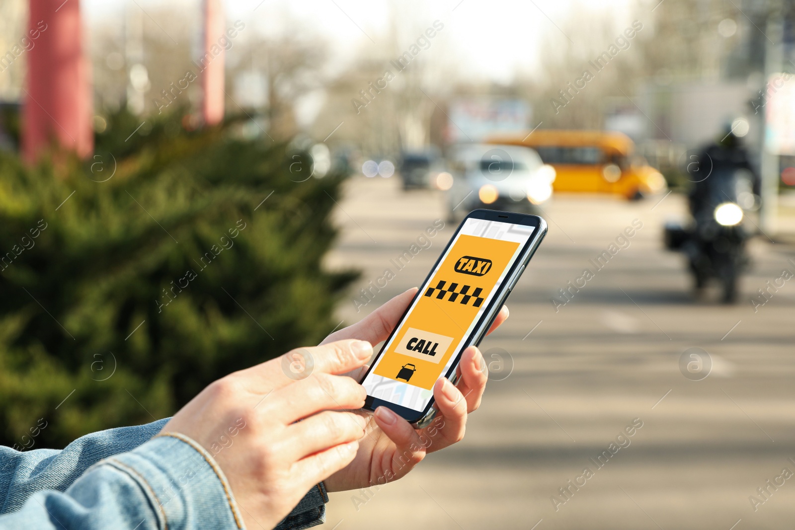 Photo of Woman ordering taxi with smartphone on city street, closeup