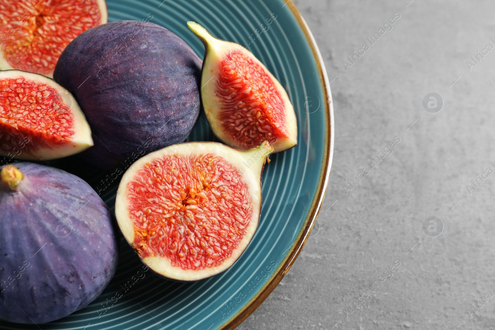 Photo of Plate with fresh ripe figs on gray background, top view