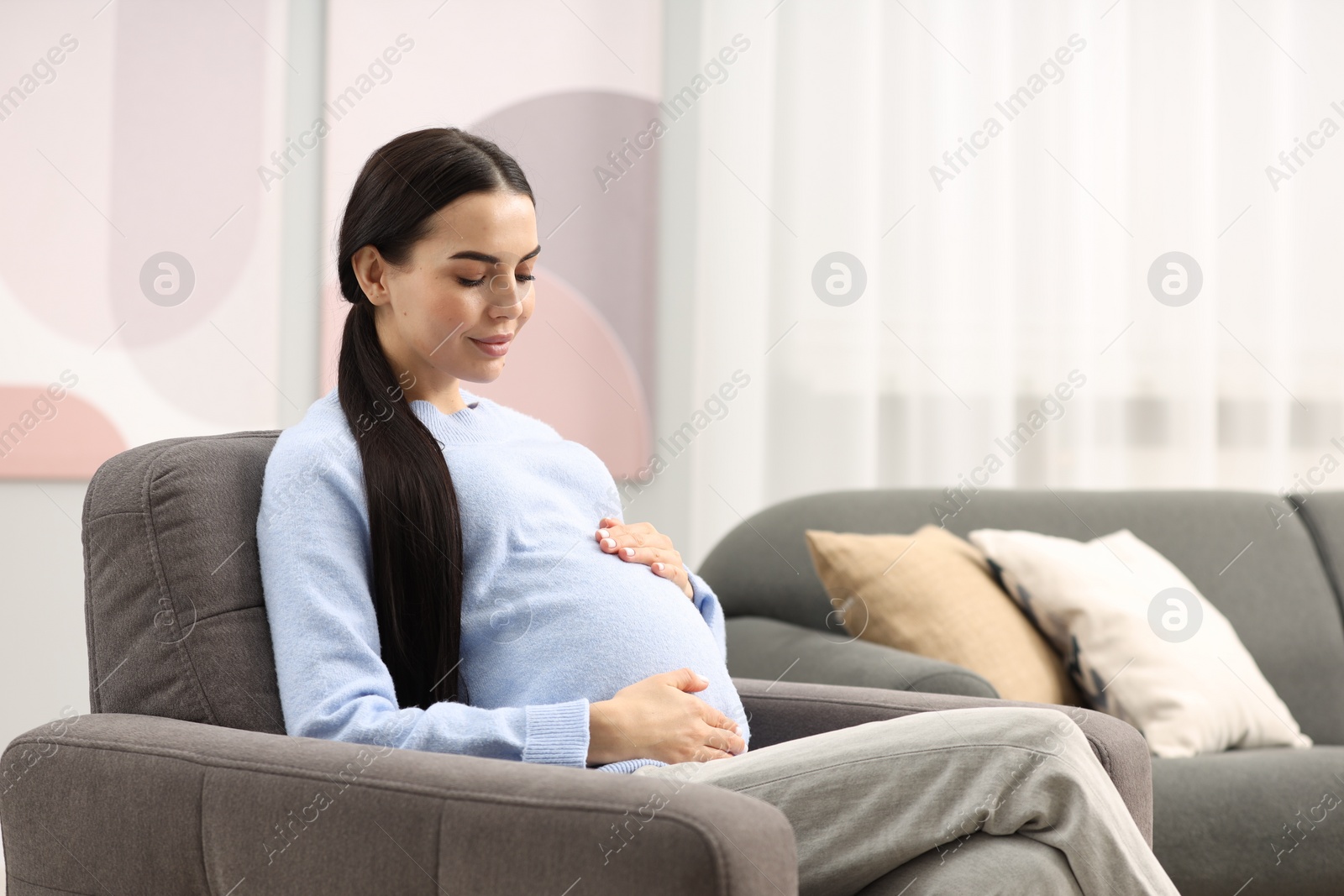 Photo of Pregnant young woman on armchair at home