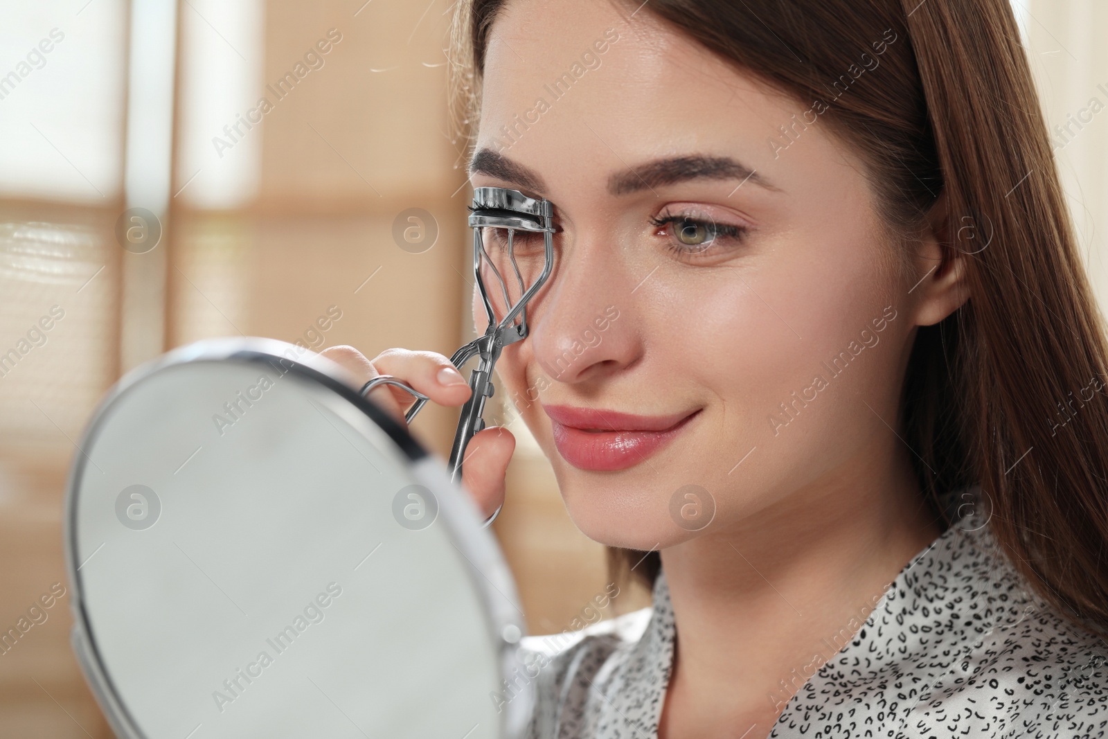 Photo of Woman using eyelash curler near mirror, closeup