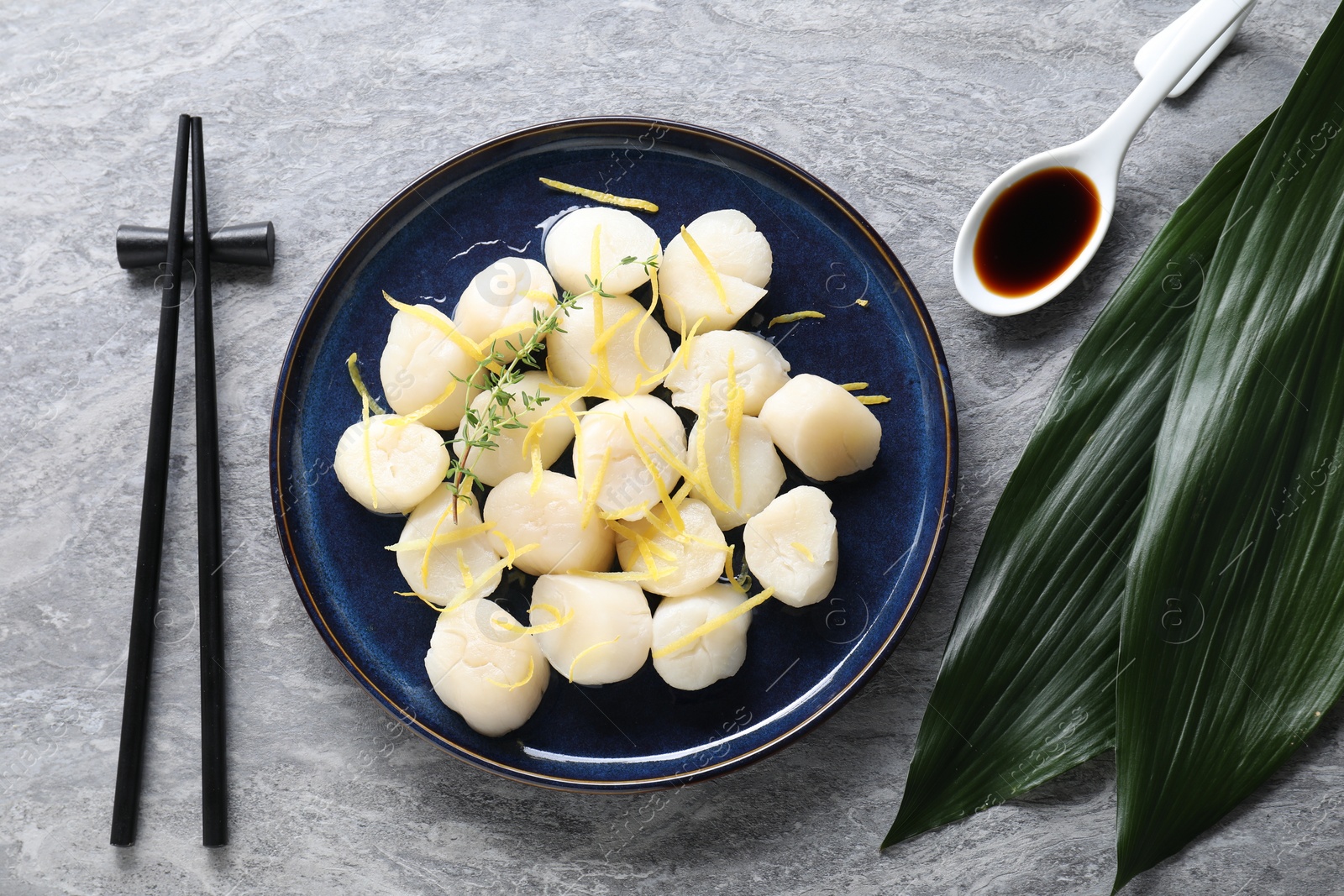 Photo of Raw scallops with thyme and lemon zest served on grey marble table, flat lay